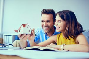image of a young couple looking to at a house with mortgage papers on the table