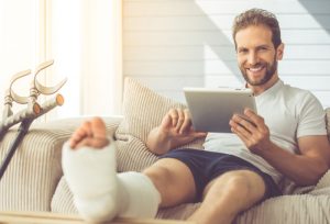 Image of a young man smiling after an accident with his leg in a cast