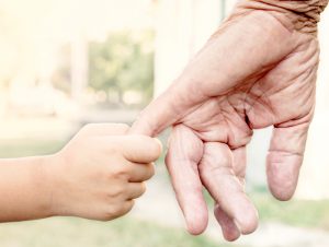 Image of a young child holding and older persons finger